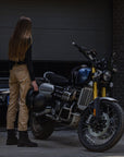 a woman standing by her motorcycle wearing beige mc pants