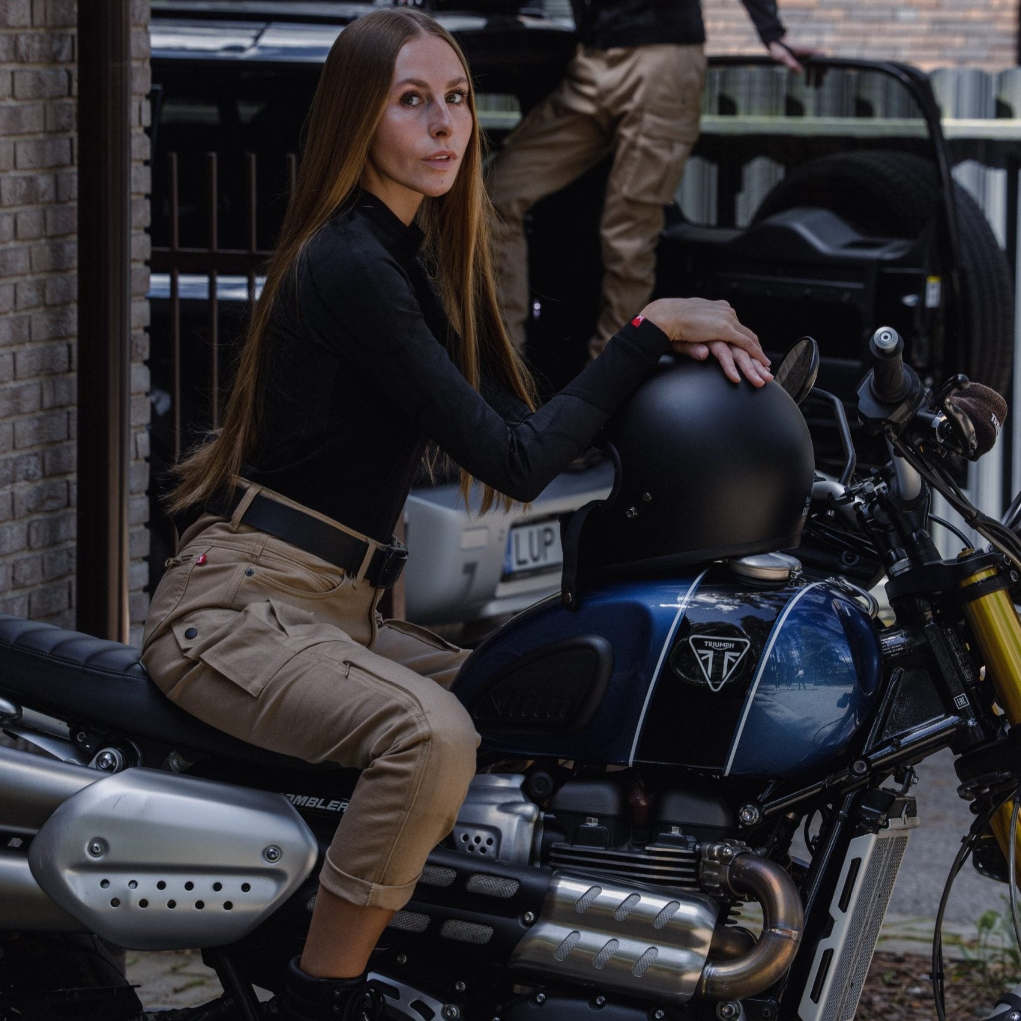 a brunette woman sitting on her motorcycle wearing beige mc pants 