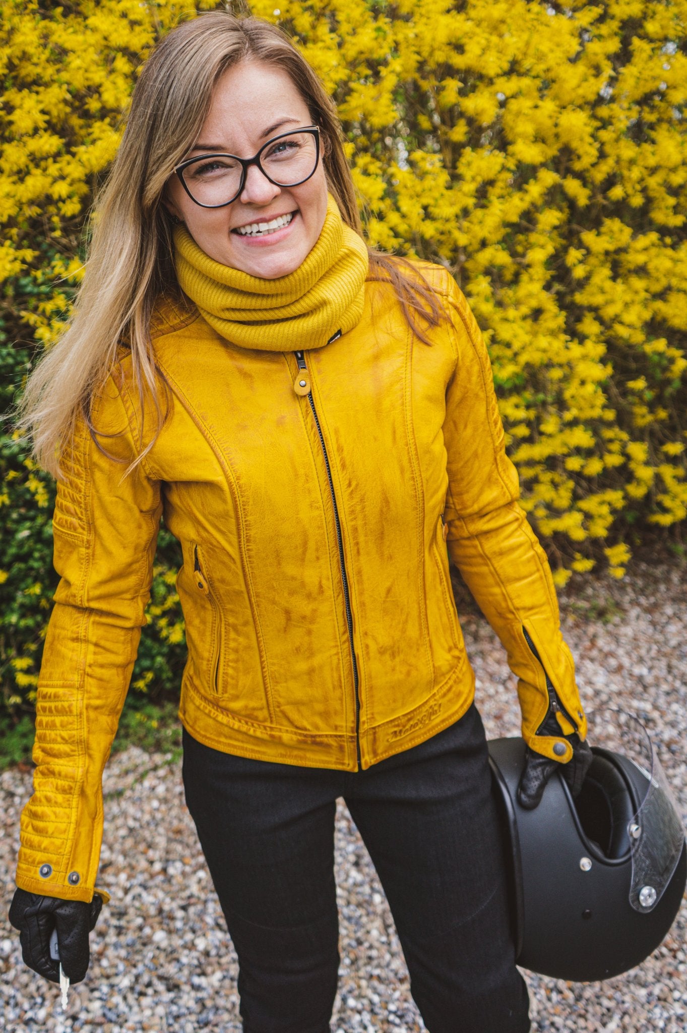 A smiling woman wearing yellow women&#39;s motorcycle leather jacket 