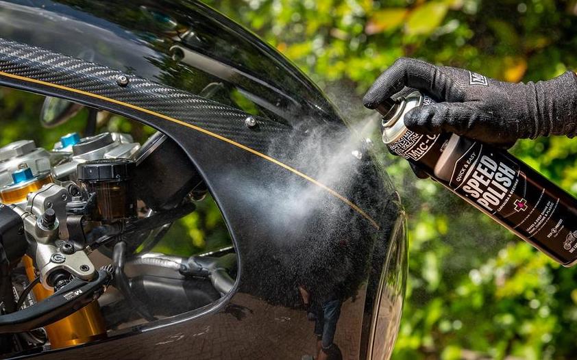 A motorcycle is being sprayed with the Muc-off motorcycle speed polish spray