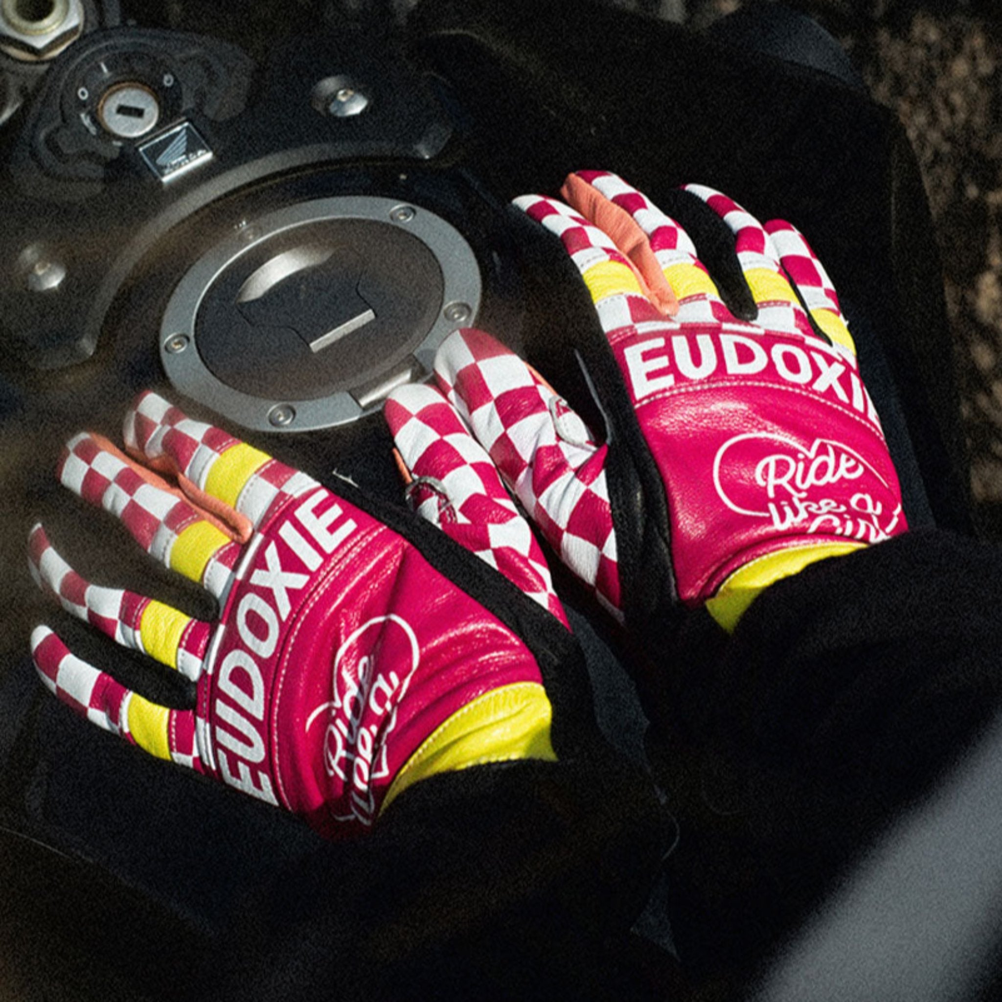 Ride like a Girl pink, black and yellow women&#39;s motorcycle gloves from eudoxie on the motorcycle&#39;s gas tank