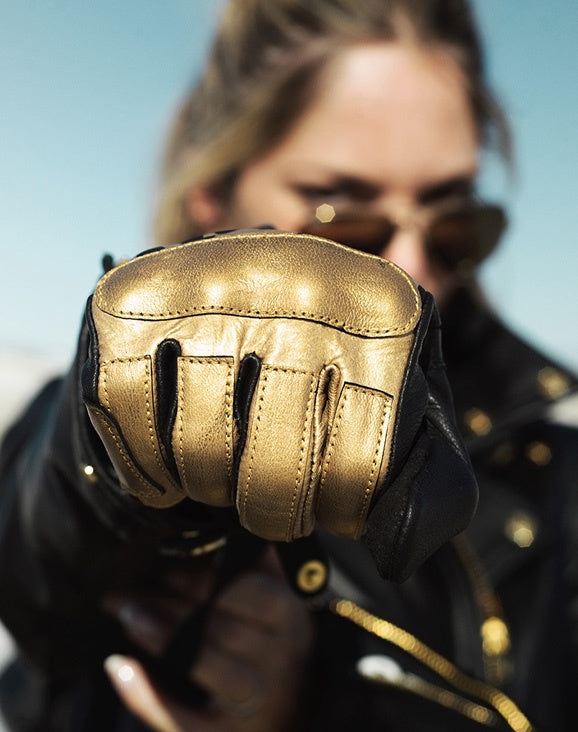woman's fist wearing black Eudoxie mc glove with golden flames 