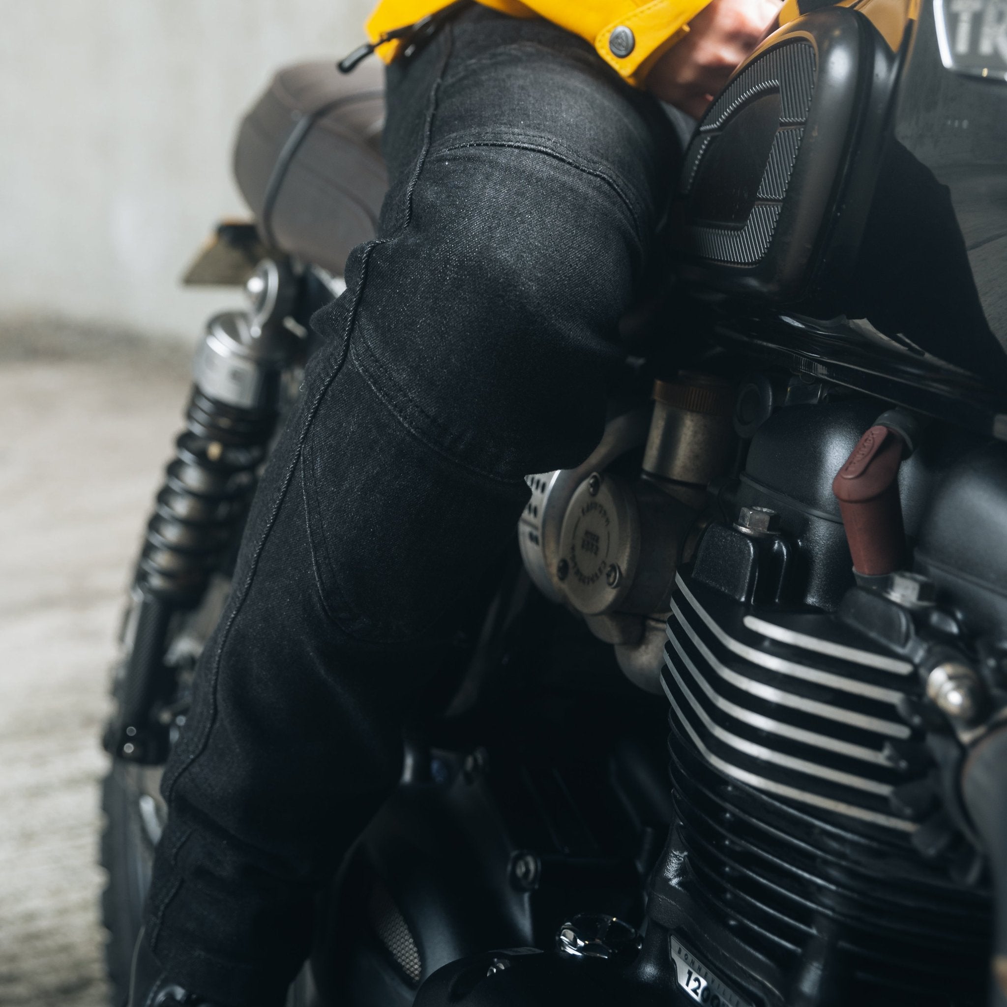 A woman&#39;s leg as she sits on a motorcycle, wearing black lady motorcycle jeans from Moto Girl.