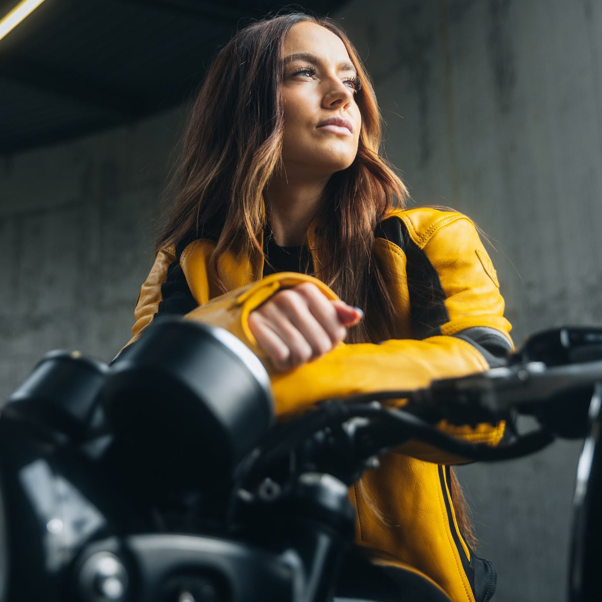 A young woman on her motorcycle wearing a yellow and black women's motorcycle jacket.