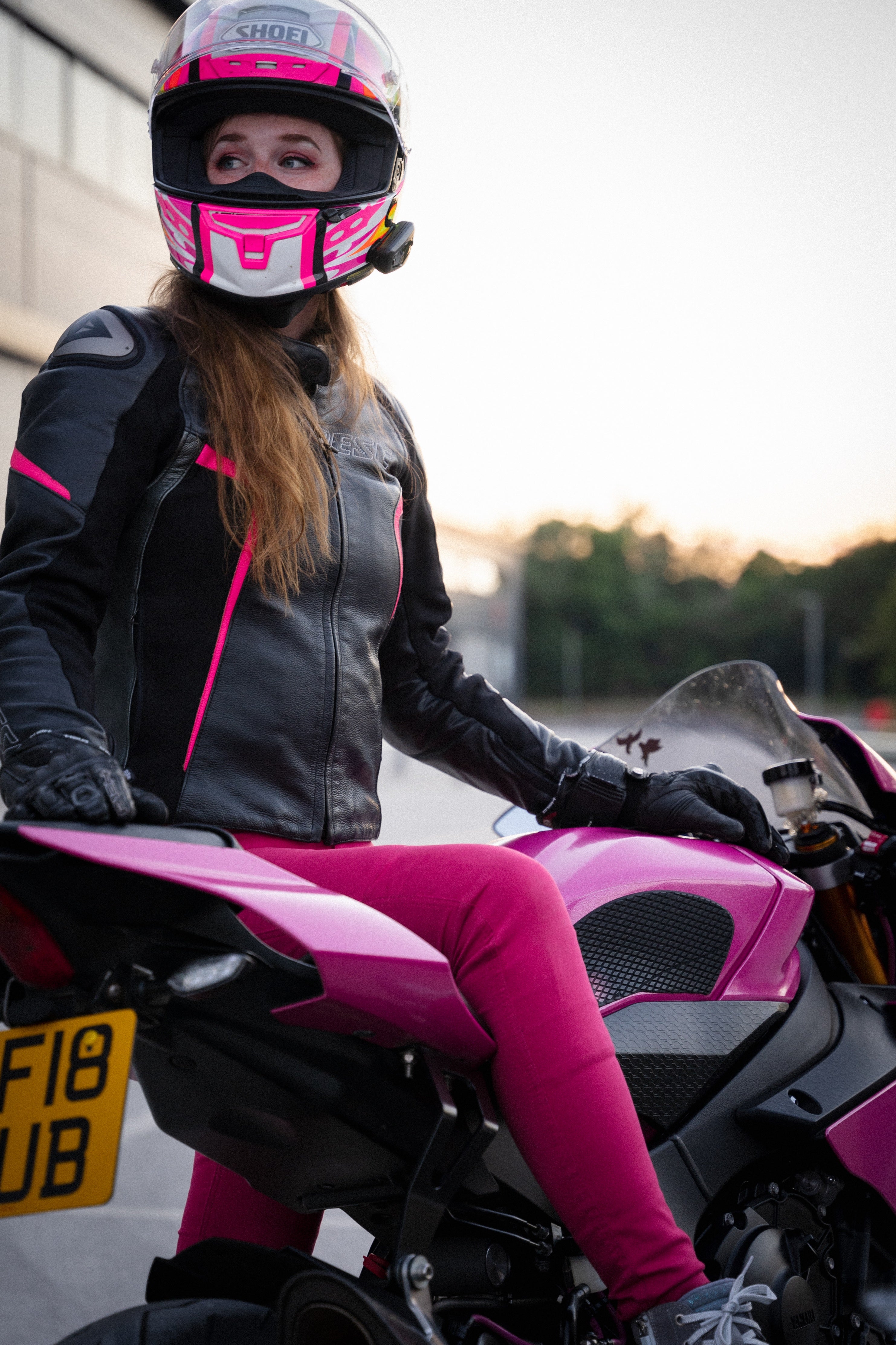 A woman wearing pink motorcycle trousers on a motorcycle 