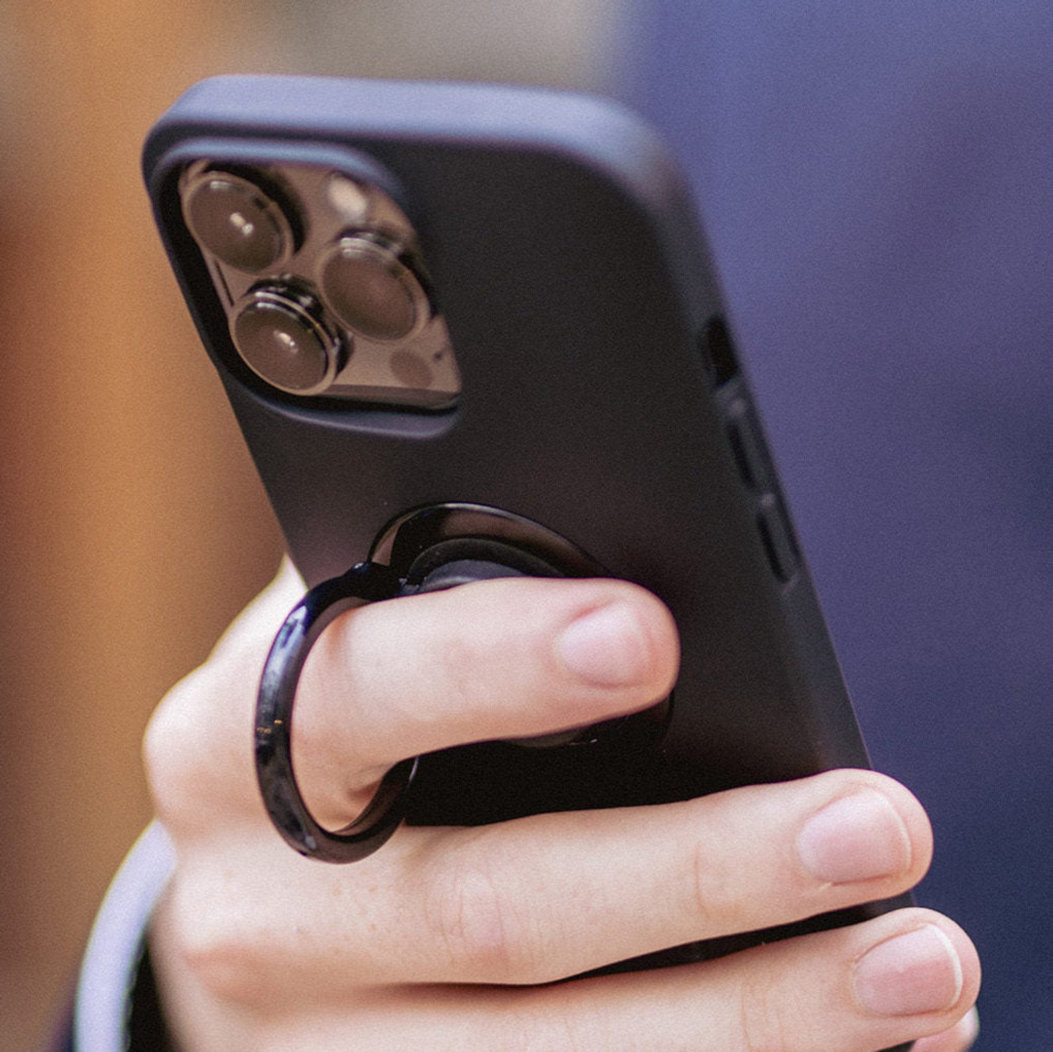 A man holding his phone using the ring holder 