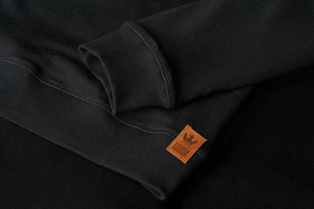 The close up of the brown patch Rugged Design on the black sweatshirt from Pando Moto 