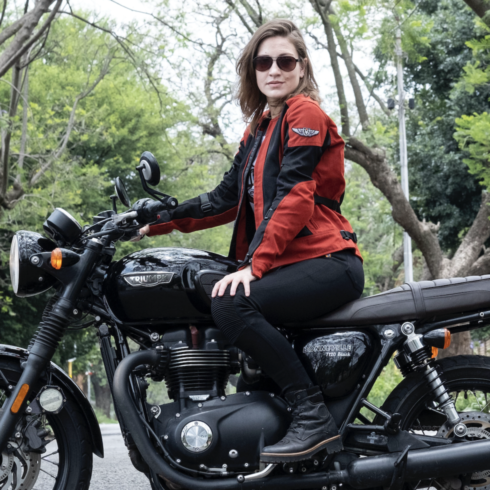a young woman on a Triumph motorcycle wearing red and black women&#39;s motorcycle summer jacket from Moto Girl 